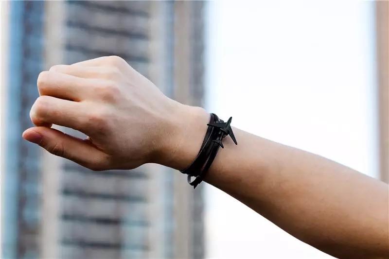 Male's forearm up in the air wearing and showing their airplane leather bracelet with photo background blur